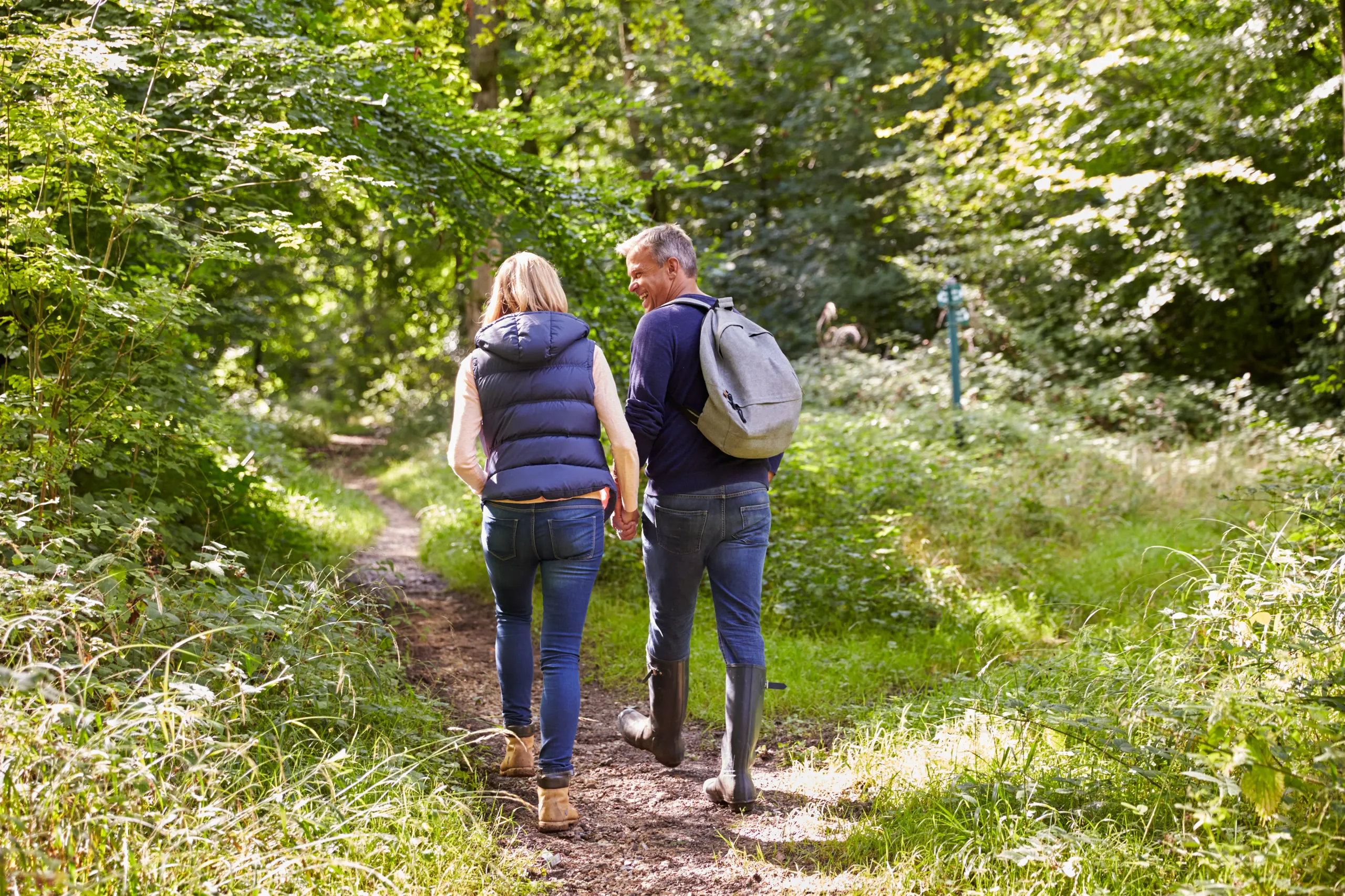 A couple walking together along a sunlit forest trail.