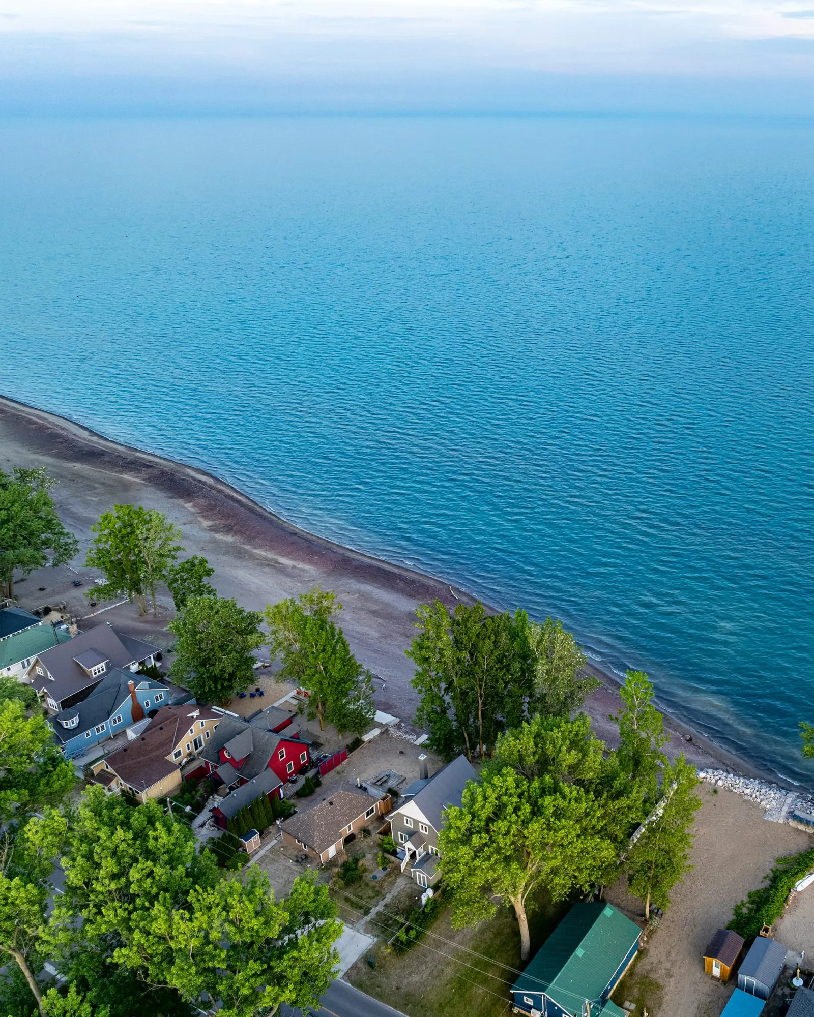 Aerial view of the Long Point shoreline on Lake Erie, with cottages among the trees beside a long curving beach.